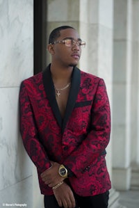 a man in a red and black suit leaning against a wall