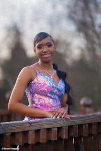 a young woman in a colorful dress posing on a railing